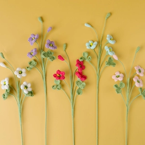 Bouquet di trifogli fatti a mano all'uncinetto con fiori colorati e foglie verdi su fondo caldo