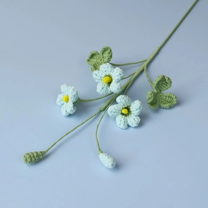 Dettaglio di bouquet di trifoglio all'uncinetto con fiori azzurri e foglie verdi