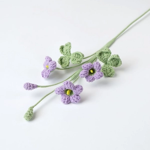 Dettaglio di fiori di trifoglio viola all'uncinetto con foglie verdi su sfondo bianco