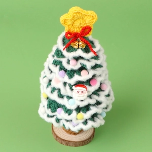 Handcrafted green crochet Christmas tree with bells and wooden base on green background