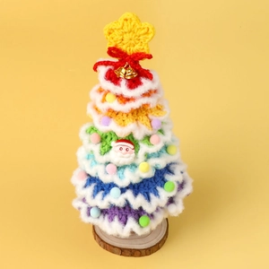 Detail of handmade crochet rainbow Christmas tree with bell on natural wood base