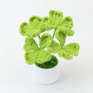 Detailed view of handmade crochet green clover in a white ceramic pot for home decor