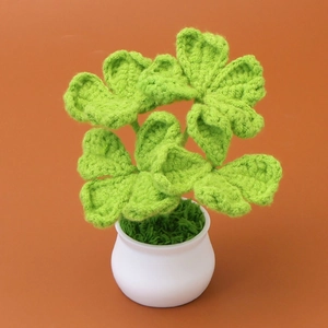 Detailed view of hand-knitted four-leaf clover crochet plant in a white ceramic pot