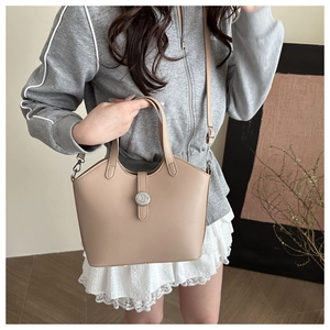 Detail of apricot matte leather bucket bag with metal logo fastener and crossbody strap