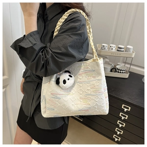 Detail of cream tote bag with colorful wave embroidery and panda plush charm accessory