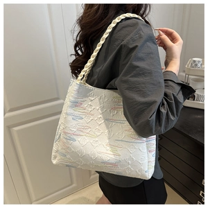 Detail of white canvas tote bag with colorful wave embroidery and woven shoulder strap