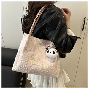 Detail of pink embossed tote bag with woven rope handle and cute panda plush charm