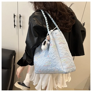 Detail of light blue textured tote bag with wave embroidery and panda plush pendant
