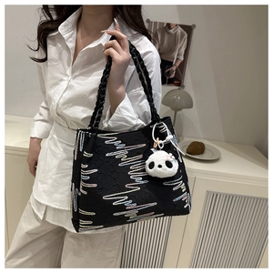 Detail of a black tote bag with colorful wave embroidery and a cute panda pendant