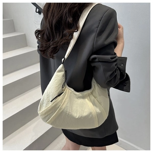 Detail of a beige crescent nylon crossbody bag showing the wide strap and smooth texture