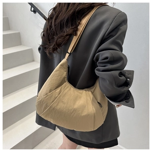 On-body view of khaki crescent tote bag with wide adjustable shoulder strap and nylon fabric