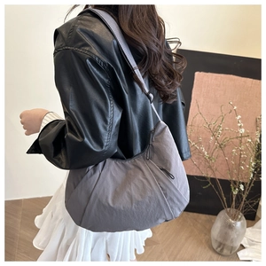 Detail view of the soft pleated texture and semi-circle shape of the dark gray crossbody bag