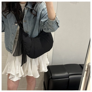 Détail d'un sac demi-lune en nylon noir avec texture plissée et large bandoulière souple