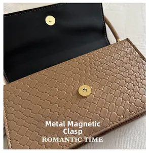 Macro detail of brown woven texture and gold magnetic snap on small square bag