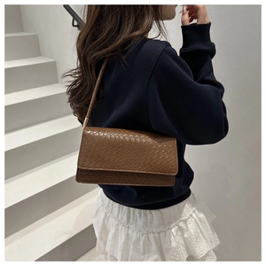 Detail of brown crocodile pattern embossed shoulder bag with gold metal hardware accents