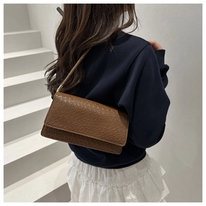 Detail of a brown faux-crocodile texture baguette bag with an elegant shoulder strap