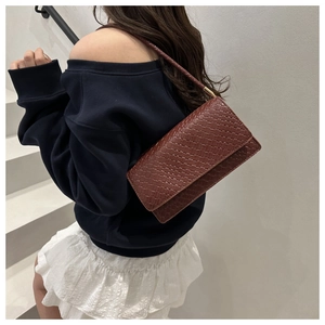 Detail view of dark brown woven pattern shoulder bag with elegant gold metal hardware