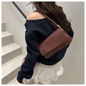 Detail of a brown woven texture baguette bag with an elegant rectangular flap design