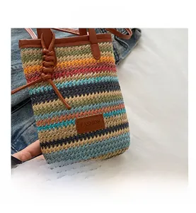 Detail of colorful woven shoulder bag with FASHION leather tag and slim brown handles