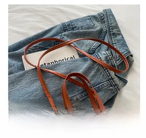 Detail of colorful striped woven summer bag with brown faux leather strap and handles