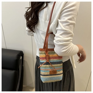 Detail of colorful striped woven bucket bag with leather strap and fashion label detail