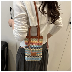 Detailed side view of a colorful striped straw crossbody bag with leather strap and fashion tag