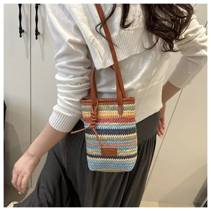 Detail of colorful striped straw woven mini bucket bag with leather brand tag and straps