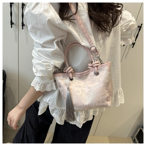 Detail of pink jacquard bag with landscape pattern, grey tassel and shoulder strap