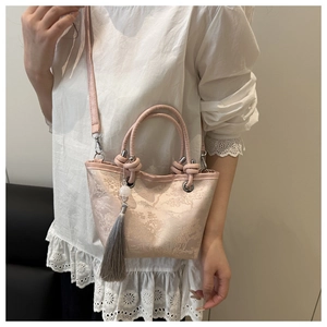 Close-up of pink jacquard crossbody bag with floral embroidery and elegant grey tassel