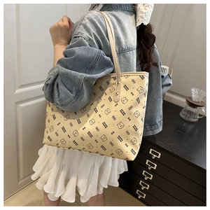 Detail of beige tote bag featuring cute cartoon bear prints and textured faux leather finish