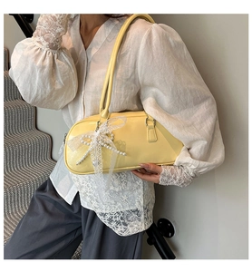 Bolso de hombro en cuero amarillo pálido con lazo de encaje blanco y detalles de perlas