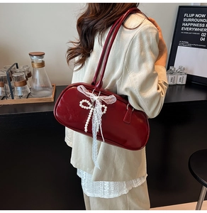 Detalle del bolso baguette rojo estilo ballet con lazo de perlas y encaje suave