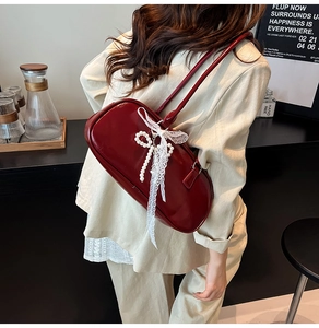 Detalle de bolso de hombro rojo brillante con lazo de perlas y cinta de encaje fino