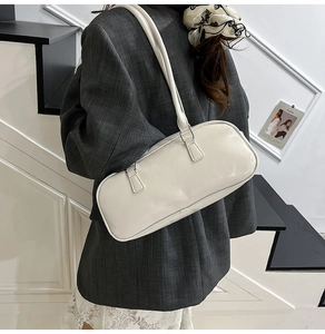 Detalle de bolso de hombro crema con textura de cuero sintético fino y correas dobles