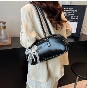 Detalle de bolso de hombro en cuero negro con lazo de encaje y colgante de corazón