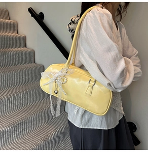 Detalle del bolso de hombro amarillo claro estilo ballet con lazo de encaje y perlas