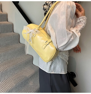 Detalle de bolso de hombro amarillo con lazo de encaje y perla llevado por una modelo