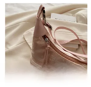 Detail of smooth metal zipper closure on a light pink lace bucket bag with 3D butterflies
