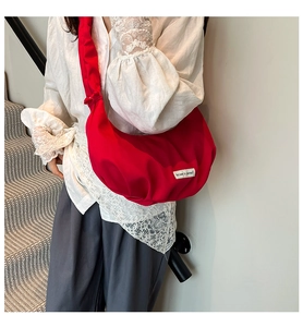 Detail of red crescent crossbody bag with white Believe in yourself woven label