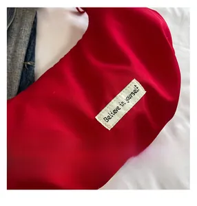 Macro shot of red pleated bag fabric with a 'Believe in yourself' woven label detail