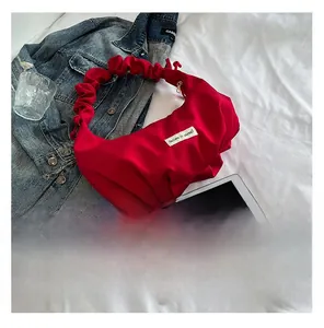 Detail of red pleated dumpling bag with 'Believe in yourself' patch on white fabric