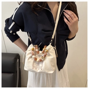 Détail du sac seau blanc à cordon avec perles marbrées et bandoulière porté par un modèle
