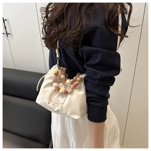 Sac seau en toile avec poignée en perles acryliques marbrées porté par un mannequin