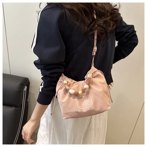 Détail du sac seau rose clair à cordon avec poignée perlée et logo Aitumi & Coole