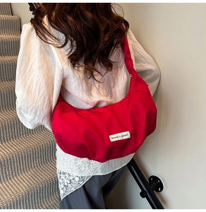 Detail of red crescent dumpling bag with decorative Believe in Yourself label on nylon