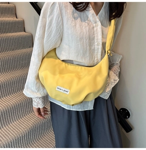 Model wearing a bright yellow crescent crossbody bag with Believe in yourself label