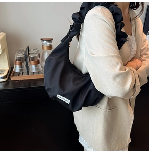 Close-up of black crescent bag featuring ruched strap and 'Believe in yourself' label