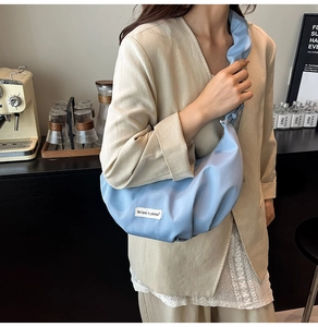Detail of light blue crescent dumpling bag with pleated texture and ruffle shoulder strap