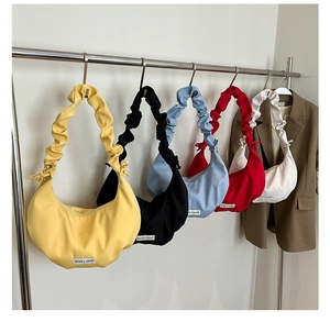Row of colorful crossbody bags featuring pleated cloud-like straps and woven labels