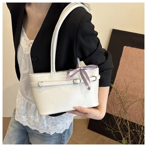 Détail du sac à bandoulière blanc avec nœud rose à carreaux et boucles métalliques